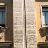 Tale separazione si sviluppa anche in verticale e in modo alternato tra le finestre, attraverso paraste binate in pietra bianca inglobate nel prospetto